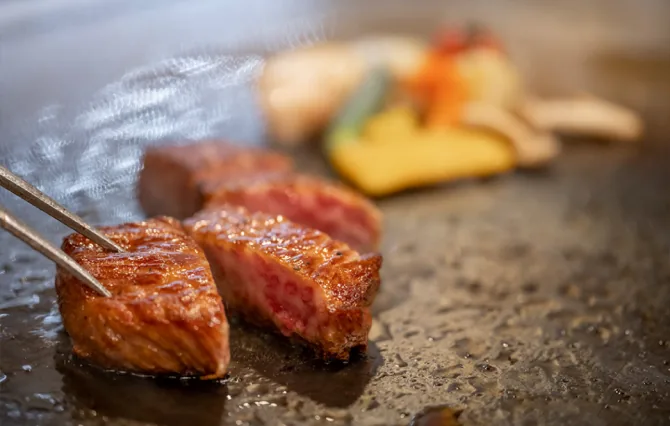 熟練シェフが鉄板で肉を焼く様子