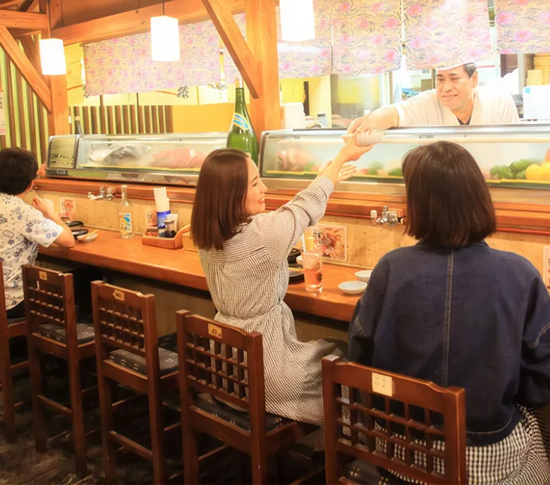 カウンター越しに料理を手渡す店主とお客さま